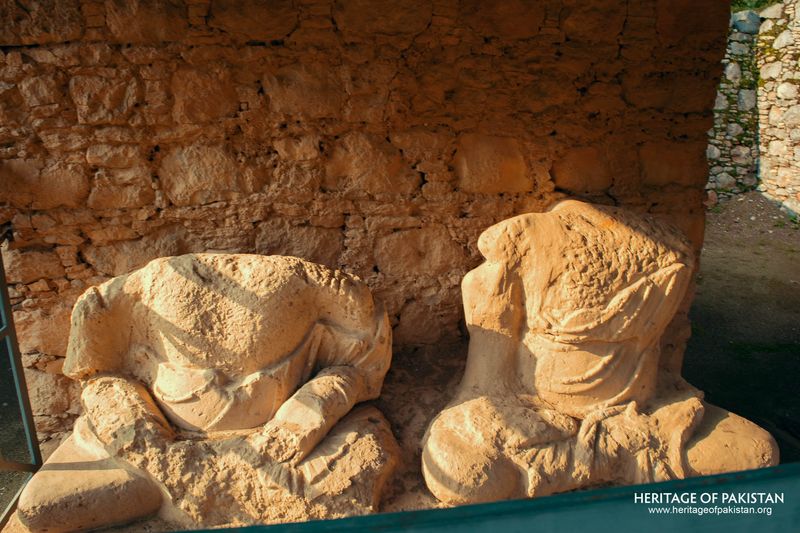 Weathered sculptural heads rest in shadowed stone niche.